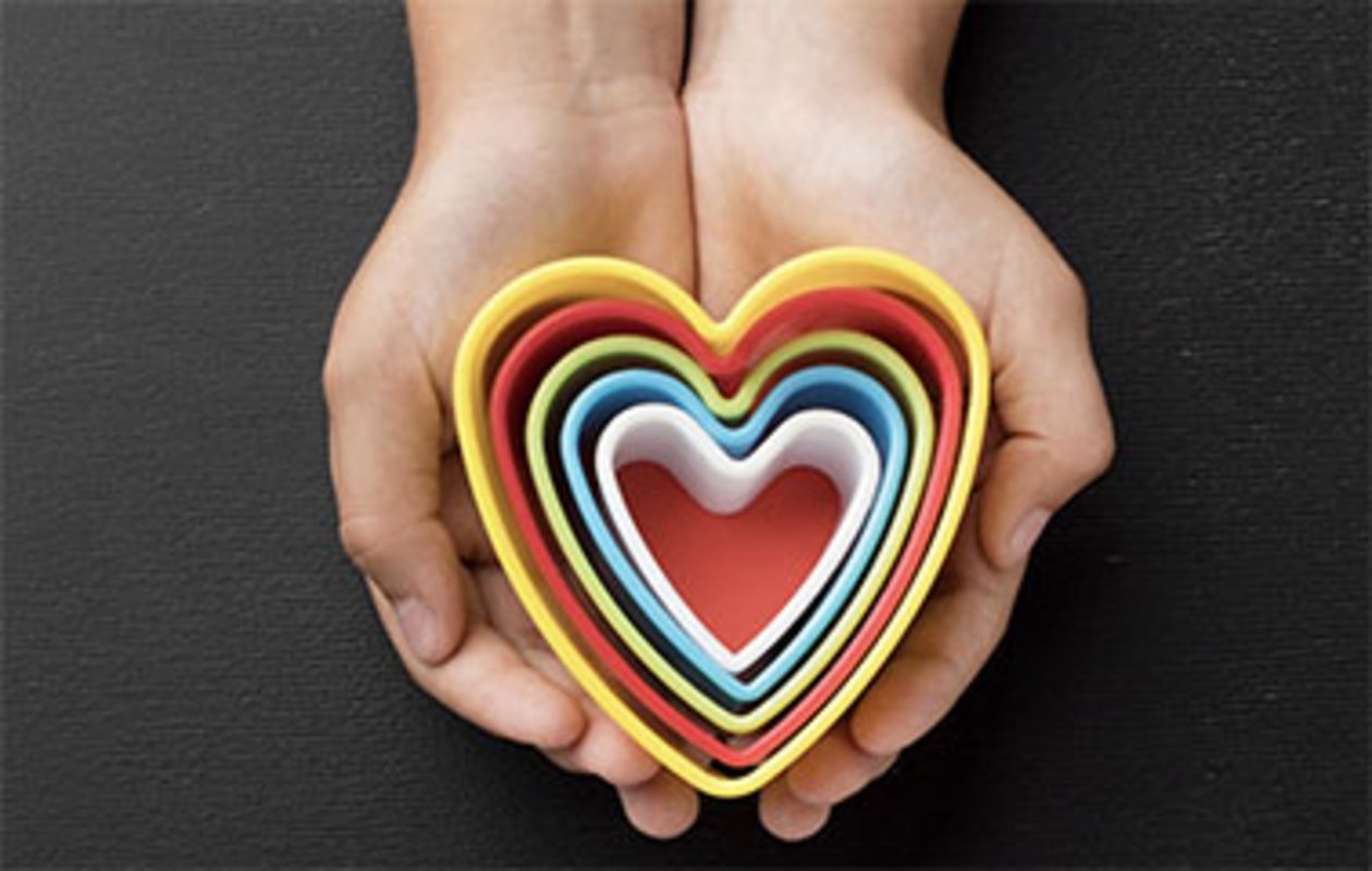 Des mains tenant des coeurs en plastique de différentes couleurs