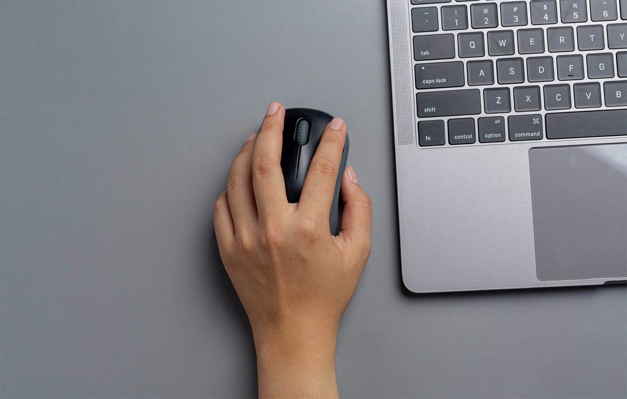 une main qui tient une souris d'ordinateur à côté d'un clavier